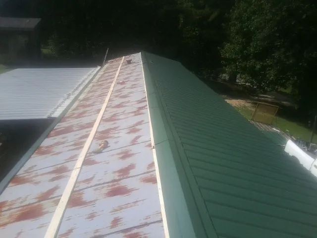 Old rusted panels beside newly installed green metal roofing — Wind Damage Roof Repair by Roofing Brothers in Eltopia